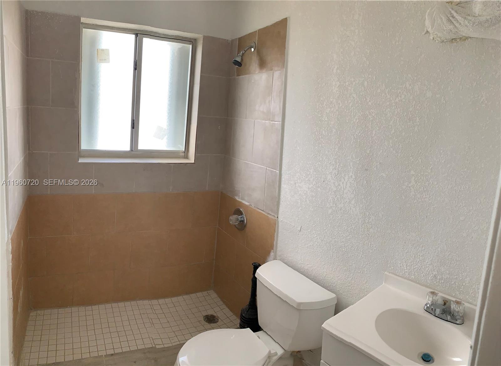 A small bathroom features a tiled walk-in shower, a white toilet, and a vanity sink — 22365 SW 115th Ct # 4, Miami FL 33170, MIAMI, FL