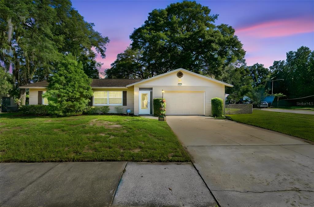 A single-story house with a beige exterior, a front-facing garage, and a concrete driveway — 1111 HELEN DRIVE, DELAND, FL