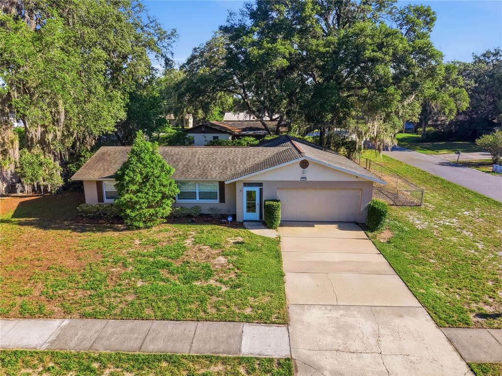 A single-story house with a beige exterior, a two-car garage, and a concrete driveway — 1111 HELEN DRIVE, DELAND, FL