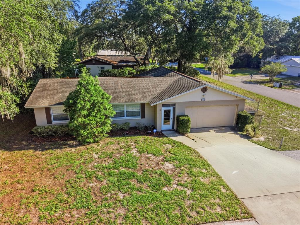 An aerial view of a single-story house with a tan exterior, shingled roof, and driveway — 1111 HELEN DRIVE, DELAND, FL