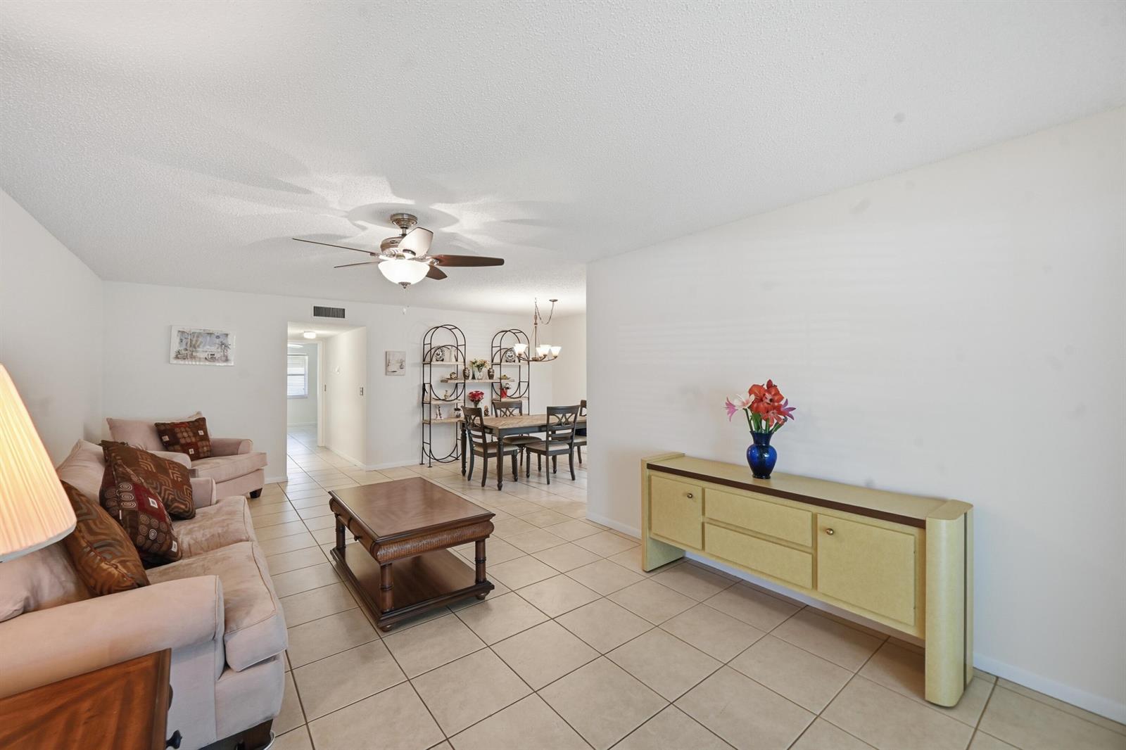 A living room with tile floors, a ceiling fan, and a dining area in the background — 14589 Canalview Drive # B, Delray Beach FL 33484, DELRAY BEACH, FL