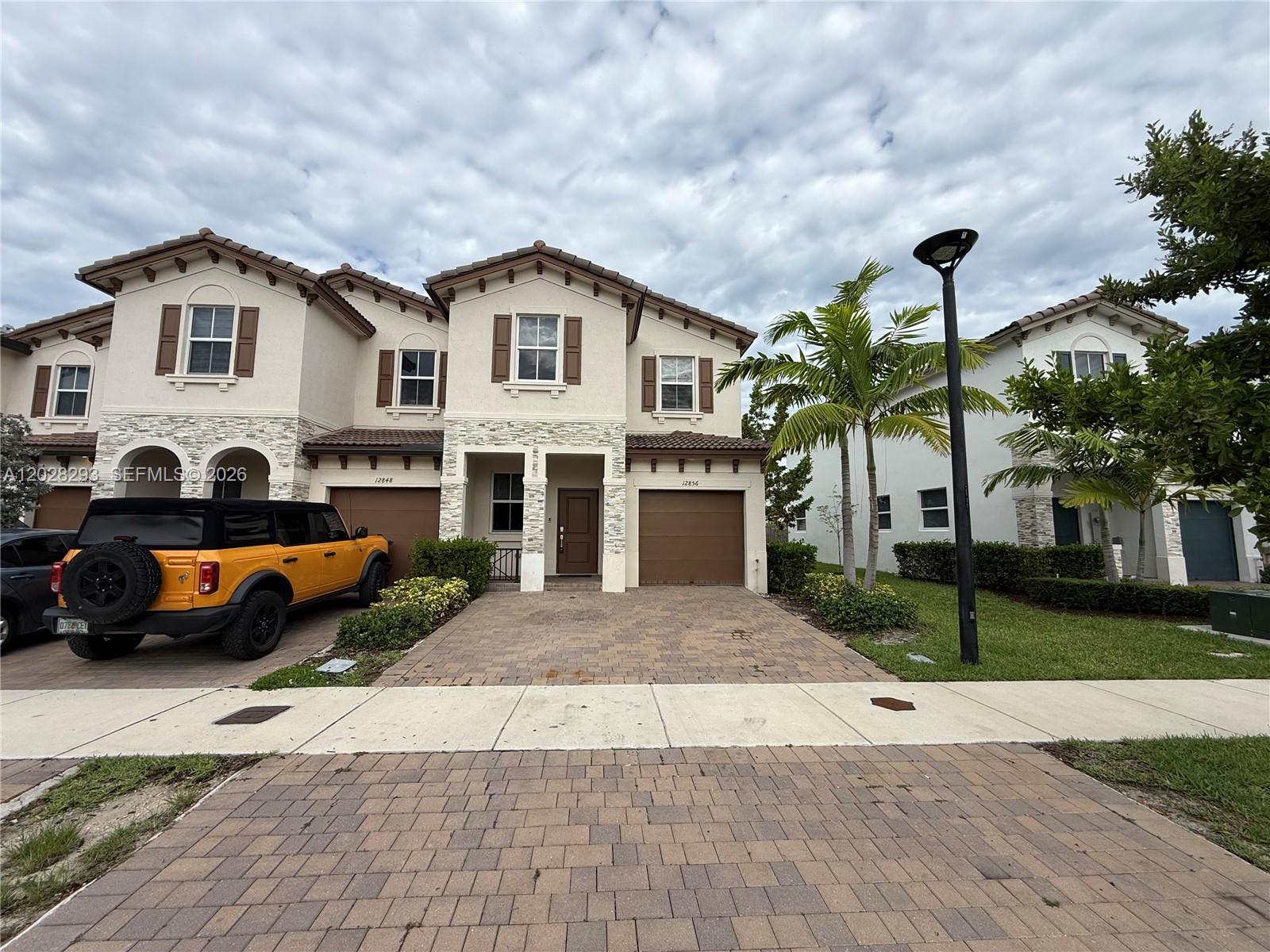 A two-story residential building with a paved driveway and an orange SUV parked outside — 12856 NW 22nd Pl # 12856, Miami FL 33167, MIAMI, FL