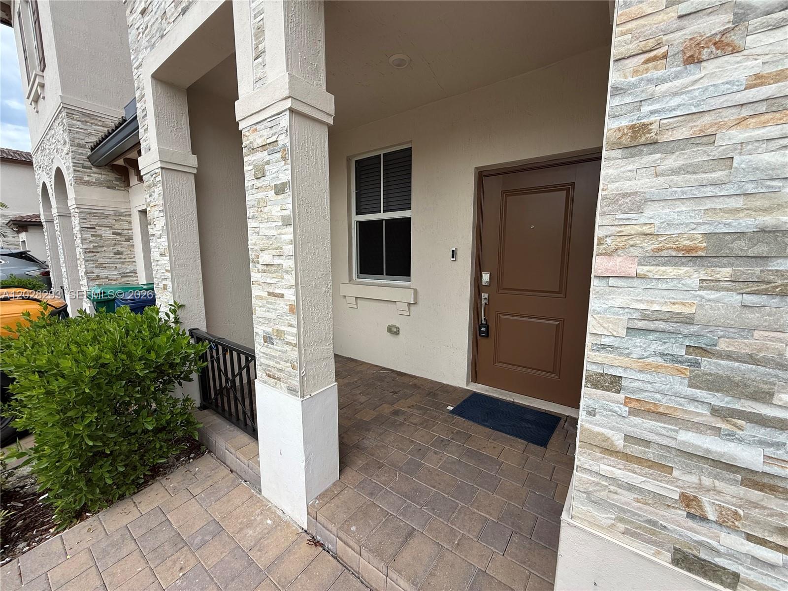 The exterior entrance features a brown door, stone-veneer columns, and a paved porch — 12856 NW 22nd Pl # 12856, Miami FL 33167, MIAMI, FL