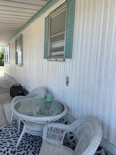 A white wicker table and chairs sit on a porch beside a mobile home exterior — 2430 SE Penny Lane, Stuart FL 34994, STUART, FL