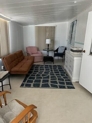 A living room features a brown futon, a pink armchair, and a patterned area rug — 2430 SE Penny Lane, Stuart FL 34994, STUART, FL
