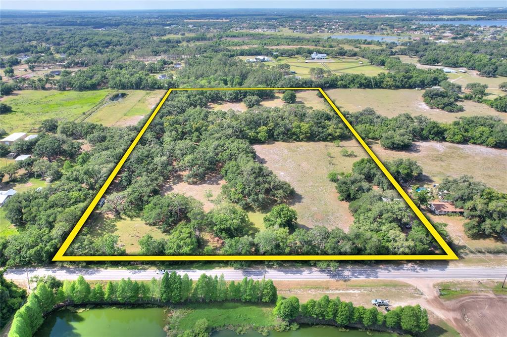 An aerial view shows a large, rectangular plot of land outlined in yellow — 12005 KNIGHTS GRIFFIN ROAD, THONOTOSASSA, FL