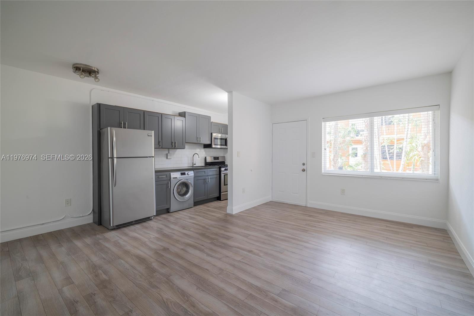 This studio apartment features a kitchen with grey cabinets, stainless steel appliances, and wood-look flooring — 7901 SW 64th Ave # 2, South Miami FL 33143, SOUTH MIAMI, FL