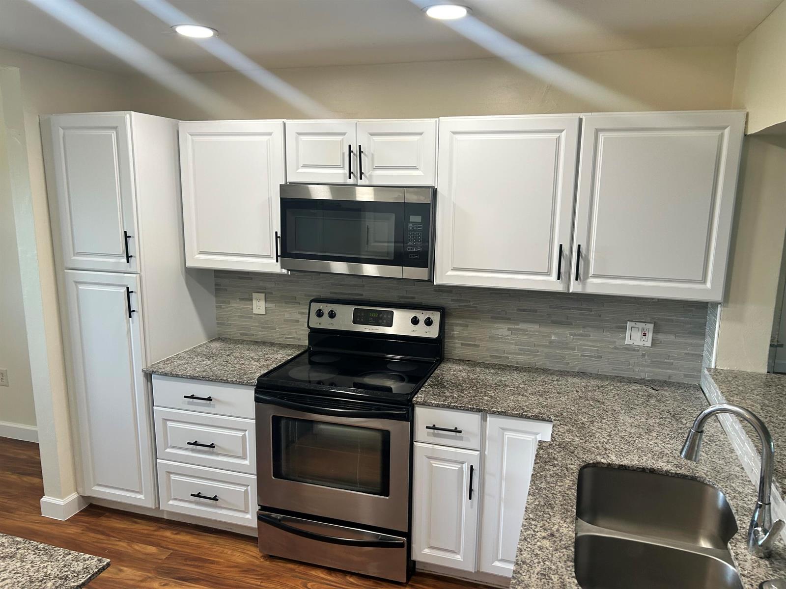 A kitchen features white cabinets, granite countertops, stainless steel appliances, and a tiled backsplash — 3521 Environ Boulevard # B503, Lauderhill FL 33319, LAUDERHILL, FL