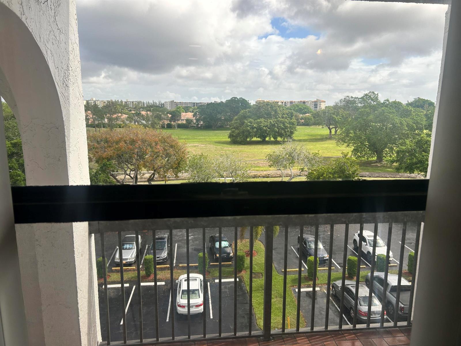 A balcony view overlooks a parking lot and a large, grassy field with trees — 3521 Environ Boulevard # B503, Lauderhill FL 33319, LAUDERHILL, FL