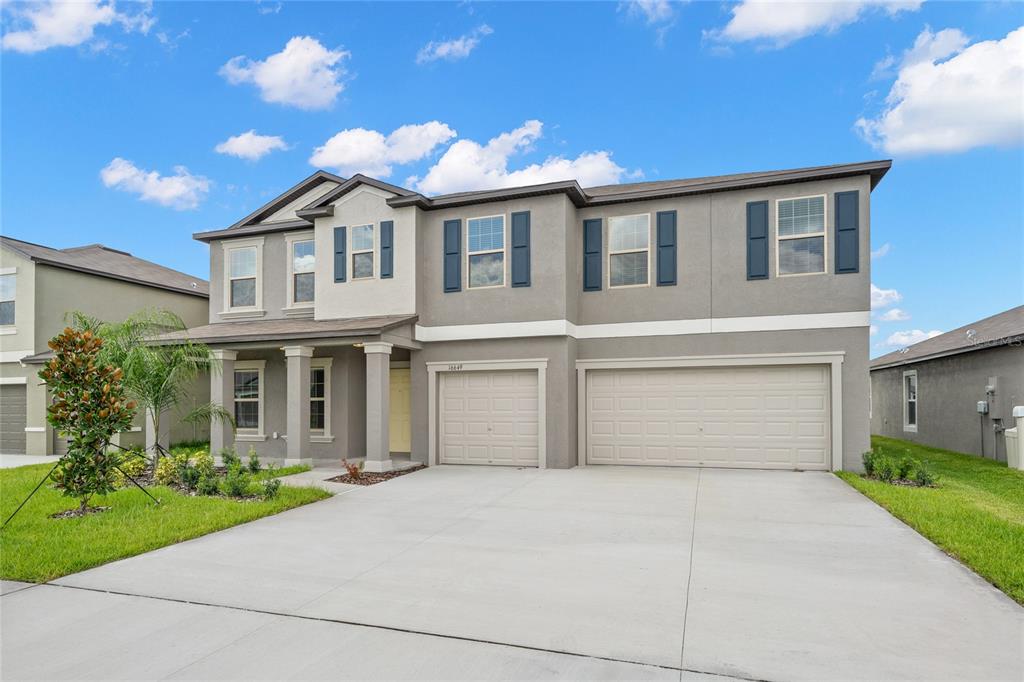A two-story house with a gray stucco exterior, blue shutters, and a three-car garage — 16649 CARLTON POND STREET, WIMAUMA, FL