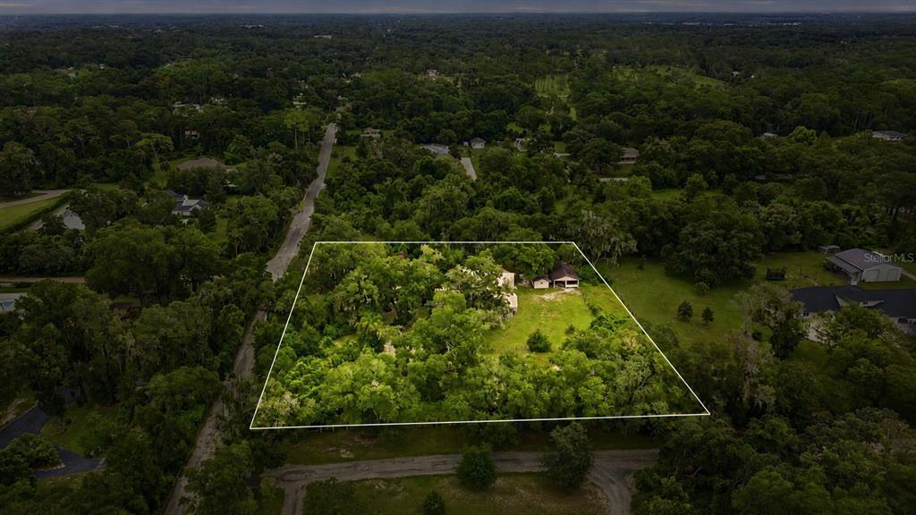 An aerial view shows a large, wooded residential lot outlined in white with a house — 1320 W TAYLOR ROAD, DELAND, FL