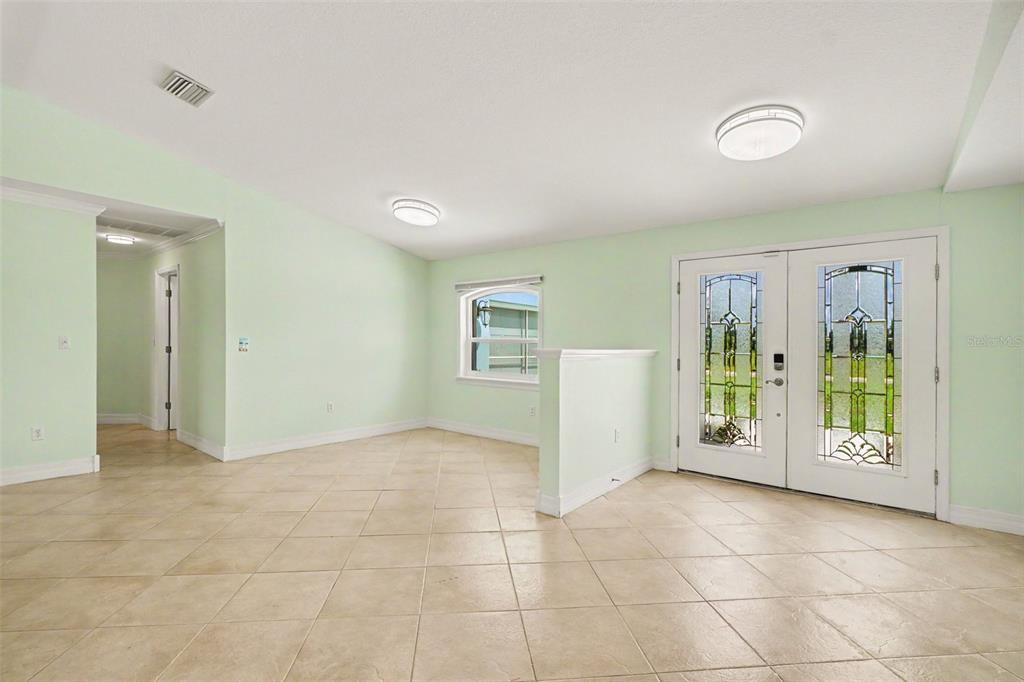 A room with light green walls, tile flooring, two ceiling lights, and double glass doors — 12001 SW KINGSWAY CIRCLE, LAKE SUZY, FL