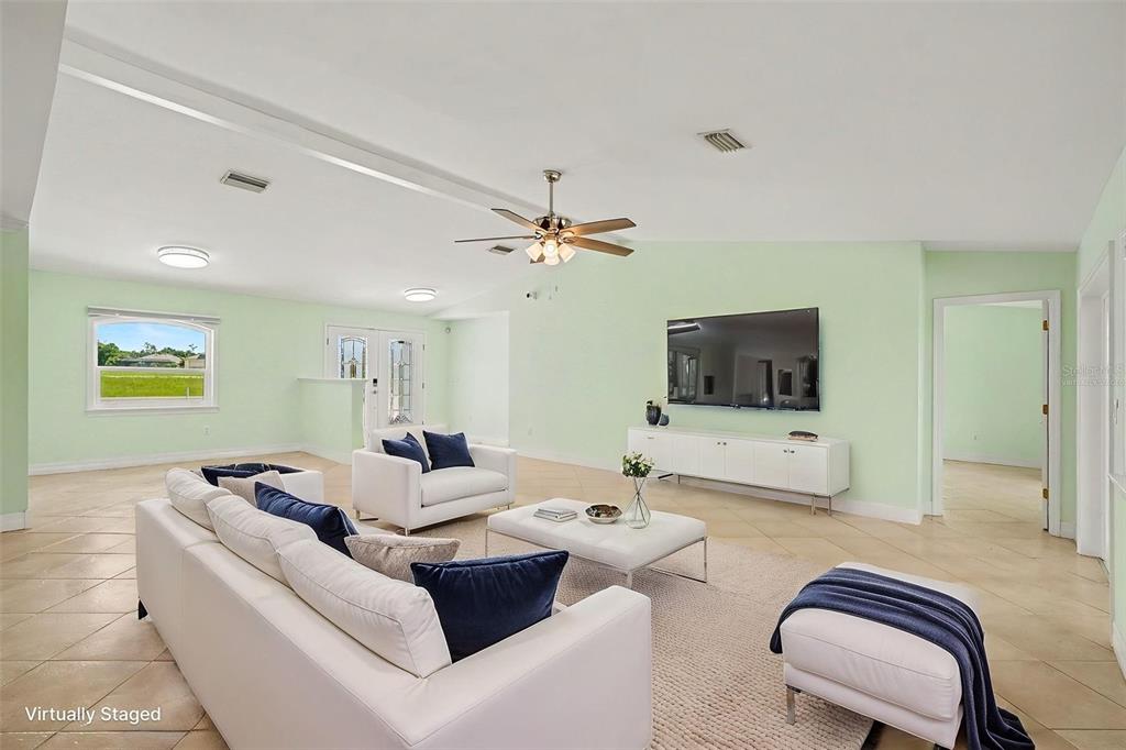 A living room with light green walls, tile flooring, and virtual staging furniture — 12001 SW KINGSWAY CIRCLE, LAKE SUZY, FL
