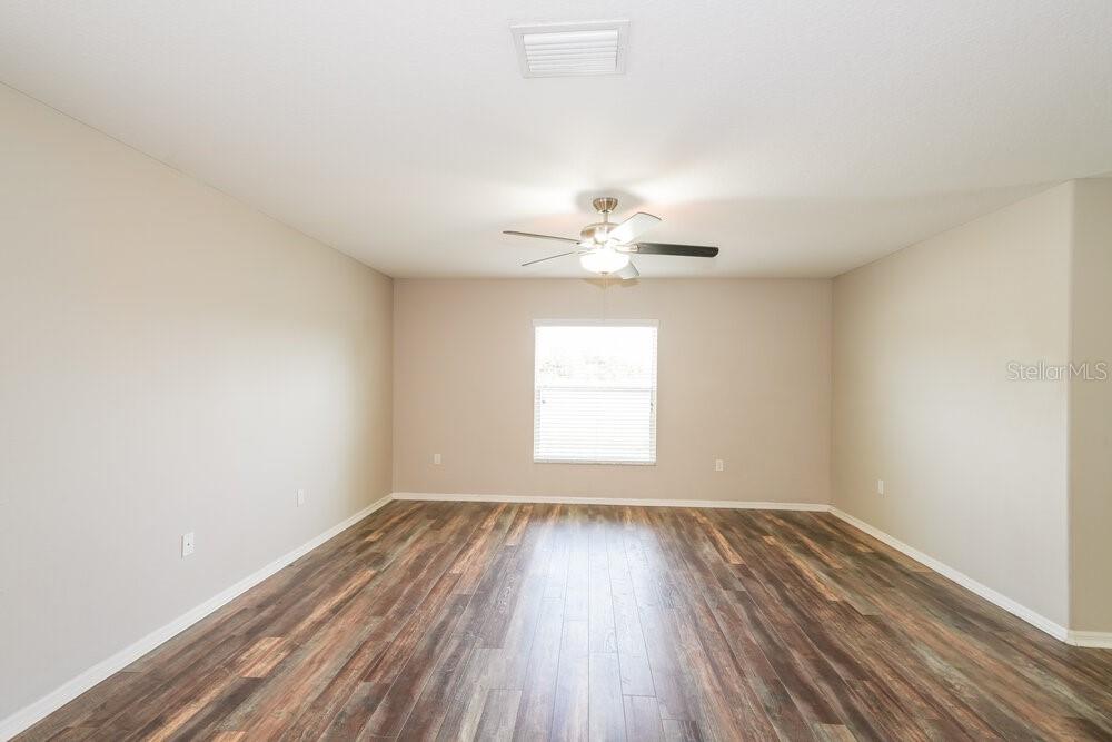 An empty room with beige walls, a ceiling fan, and wood-look flooring — 7614 MAROON PEAK DRIVE, RUSKIN, FL