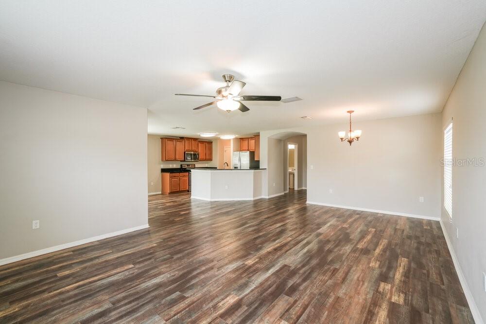 An open-concept living and dining area features wood-look flooring and a kitchen with wood cabinets — 7614 MAROON PEAK DRIVE, RUSKIN, FL