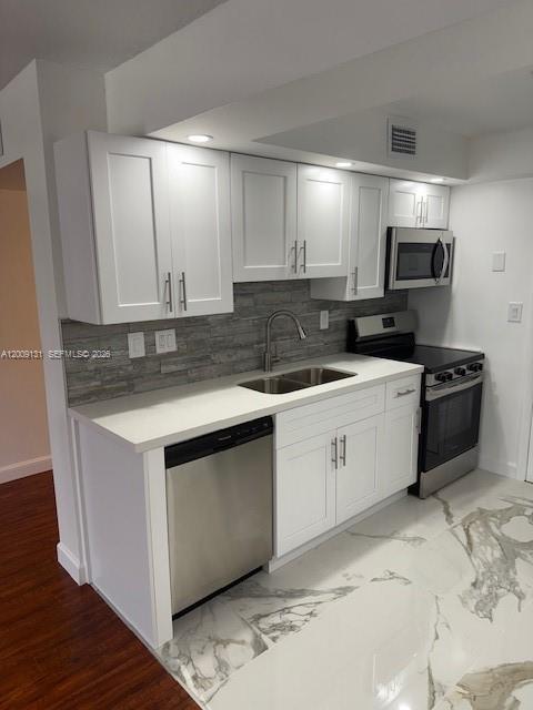 A modern kitchen features white cabinets, stainless steel appliances, a gray backsplash, and marble flooring — 1901 S Ocean Dr # 207, Hollywood FL 33019, HOLLYWOOD, FL