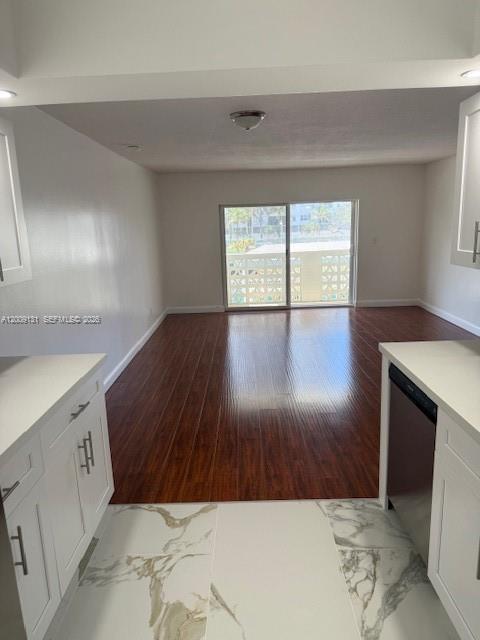 A kitchen with white cabinets and marble-look tile flooring opens into a wood-floored living area — 1901 S Ocean Dr # 207, Hollywood FL 33019, HOLLYWOOD, FL