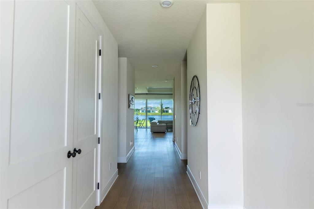 A hallway with wood-look flooring leads to a living area with a view of a lake — 6067 FOREST PERCH DRIVE, ST CLOUD, FL