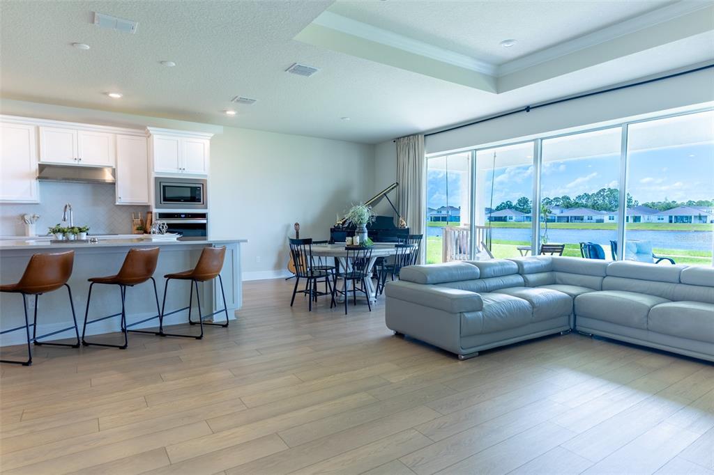 An open-concept living area features a kitchen with bar seating, a dining space, and a sofa — 6067 FOREST PERCH DRIVE, ST CLOUD, FL