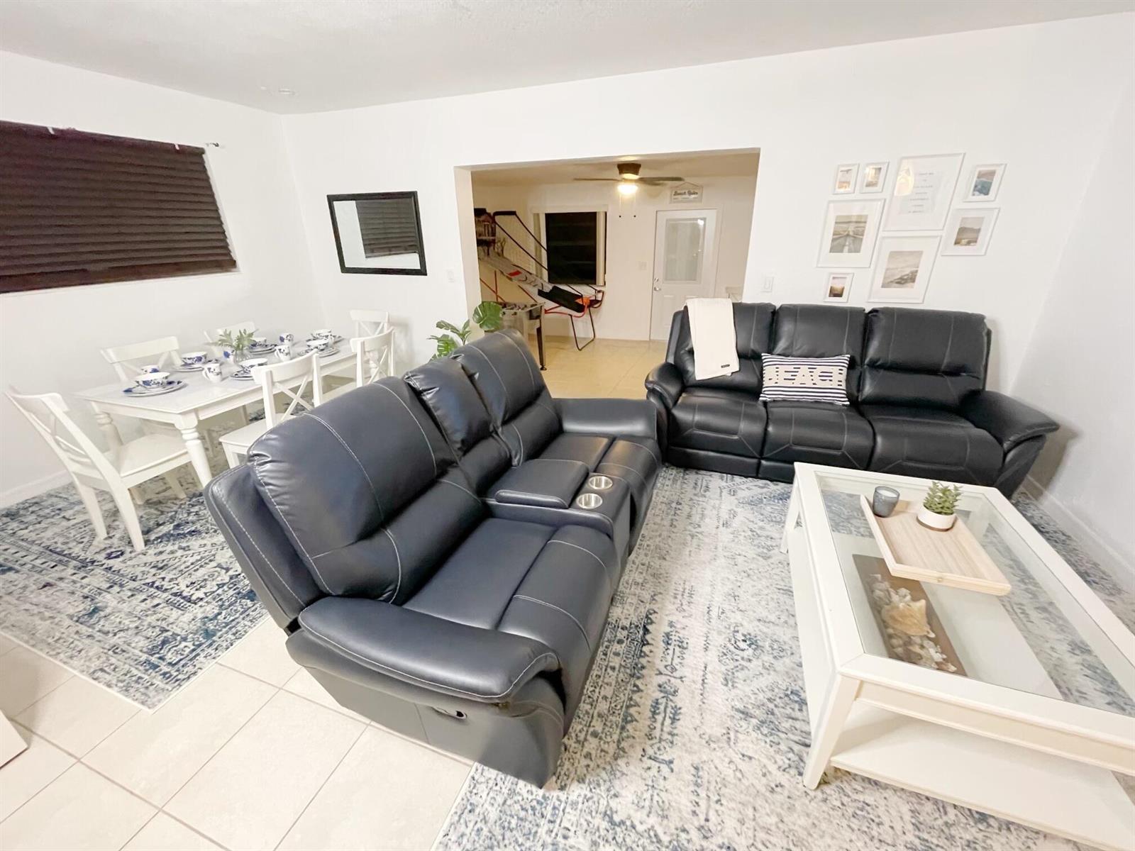 A living room and dining area feature dark leather sofas, a white coffee table, and rugs — 1067 SW 3rd Street, Hallandale Beach FL 33009, HALLANDALE BEACH, FL