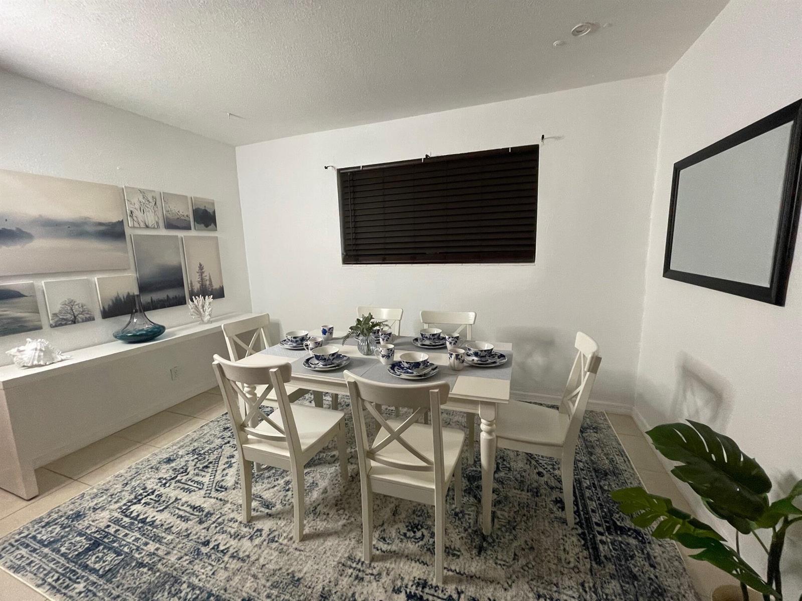 A dining room features a white table and chairs set on a blue patterned rug — 1067 SW 3rd Street, Hallandale Beach FL 33009, HALLANDALE BEACH, FL
