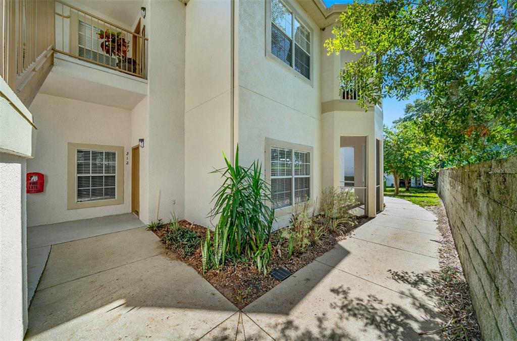 A two-story apartment building exterior features a concrete walkway, landscaping, and a fire extinguisher — 970 N SPRING GARDEN AVENUE UNIT 212, DELAND, FL