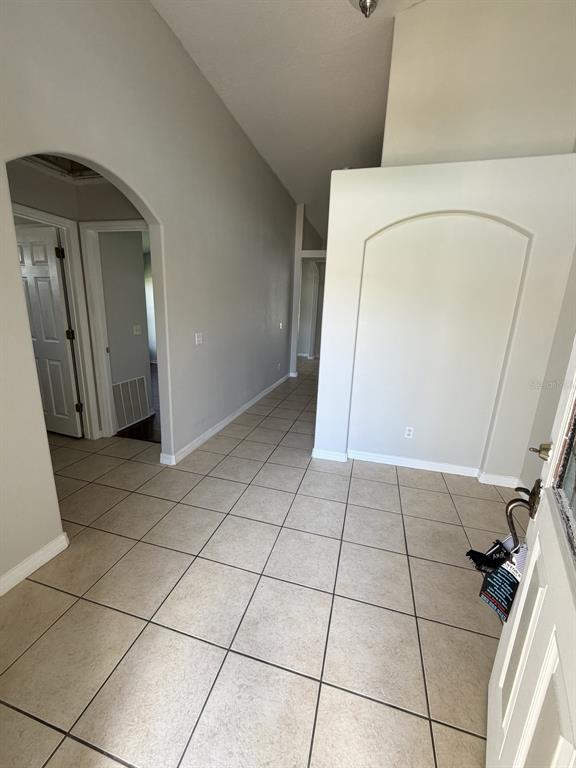 An entryway with light-colored tile flooring leads into a hallway with arched architectural details — 3035 BUCKEYE POINTE DRIVE, WINTER HAVEN, FL