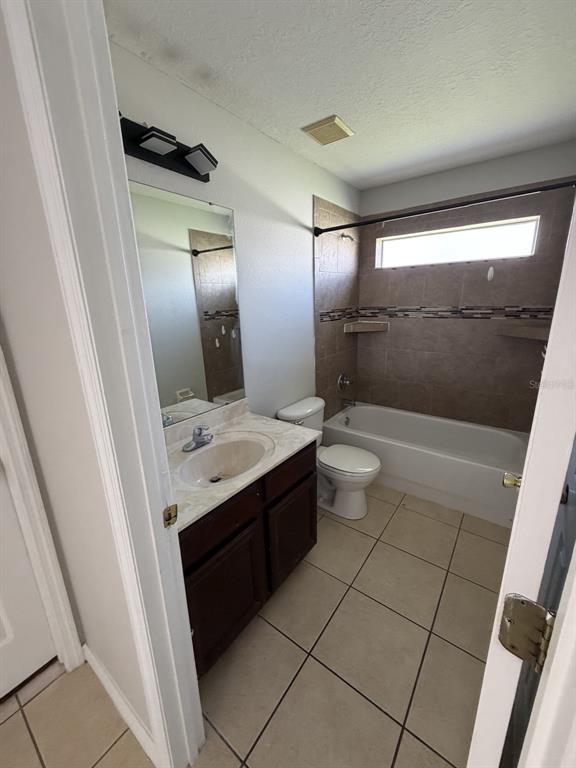 A bathroom features a dark wood vanity, a tiled shower-tub combo, and light floor tiles — 3035 BUCKEYE POINTE DRIVE, WINTER HAVEN, FL