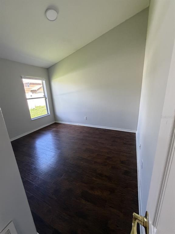 An empty bedroom with dark wood-look flooring, light gray walls, and a vaulted ceiling — 3035 BUCKEYE POINTE DRIVE, WINTER HAVEN, FL