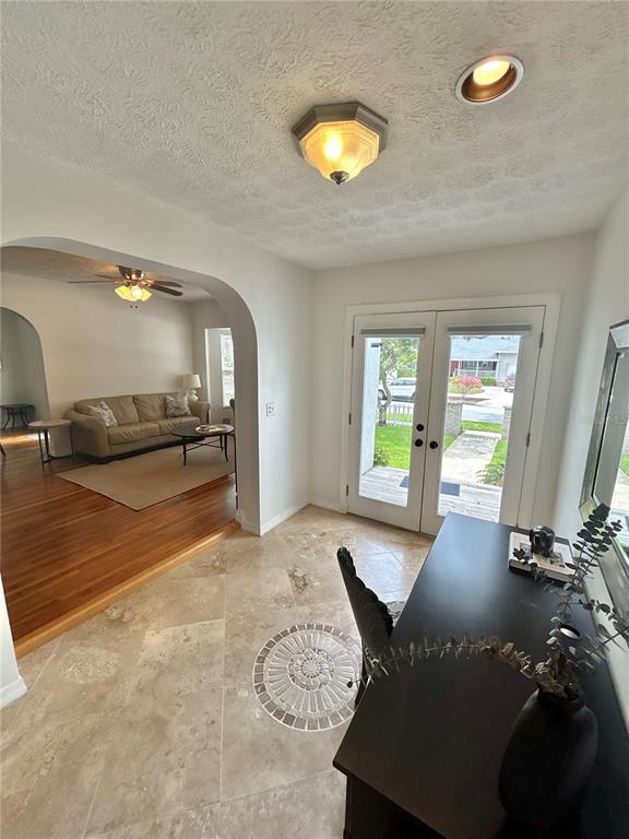 An entryway with travertine tile flooring leads through an arched opening into a living room — 3014 W MASON STREET UNIT A, TAMPA, FL