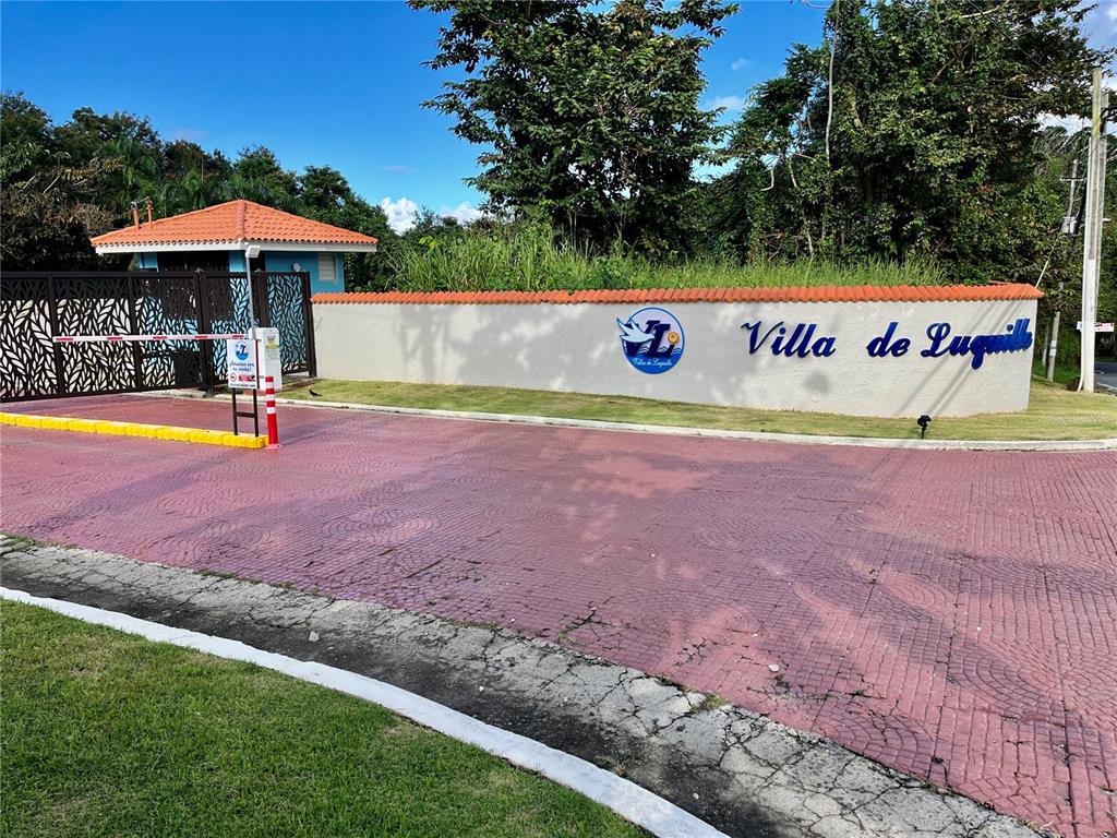 The entrance to Villa de Lugillo features a gated driveway, a security booth, and signage — Urb. Villas de Luquillo C 15, LUQUILLO, PR
