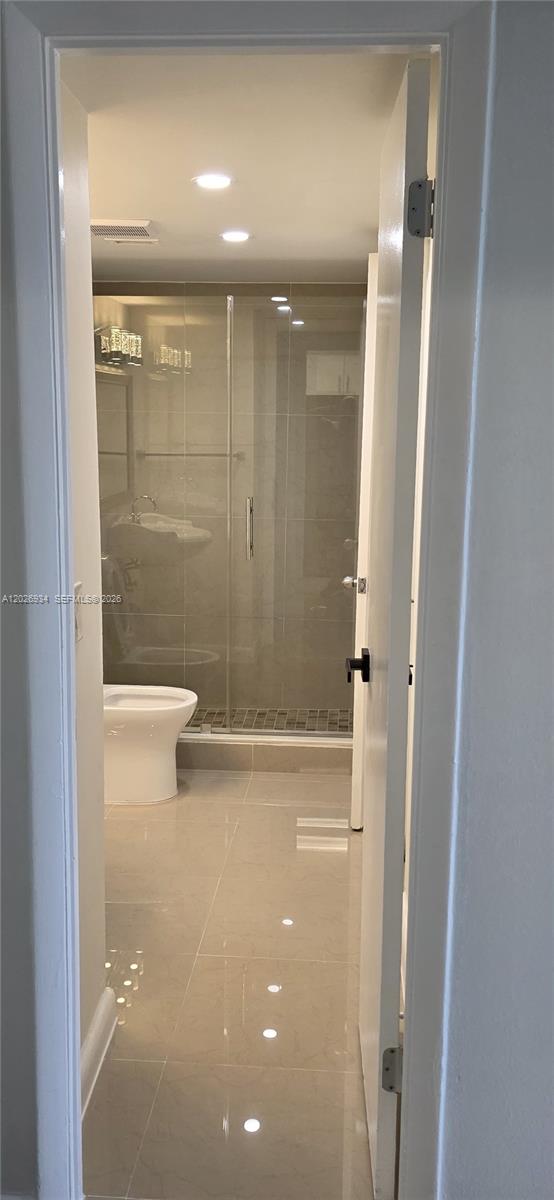 A modern bathroom features a glass-enclosed shower, a white toilet, and light-colored tile flooring — 492 NW 165th St Rd # 511, Miami FL 33169, MIAMI, FL