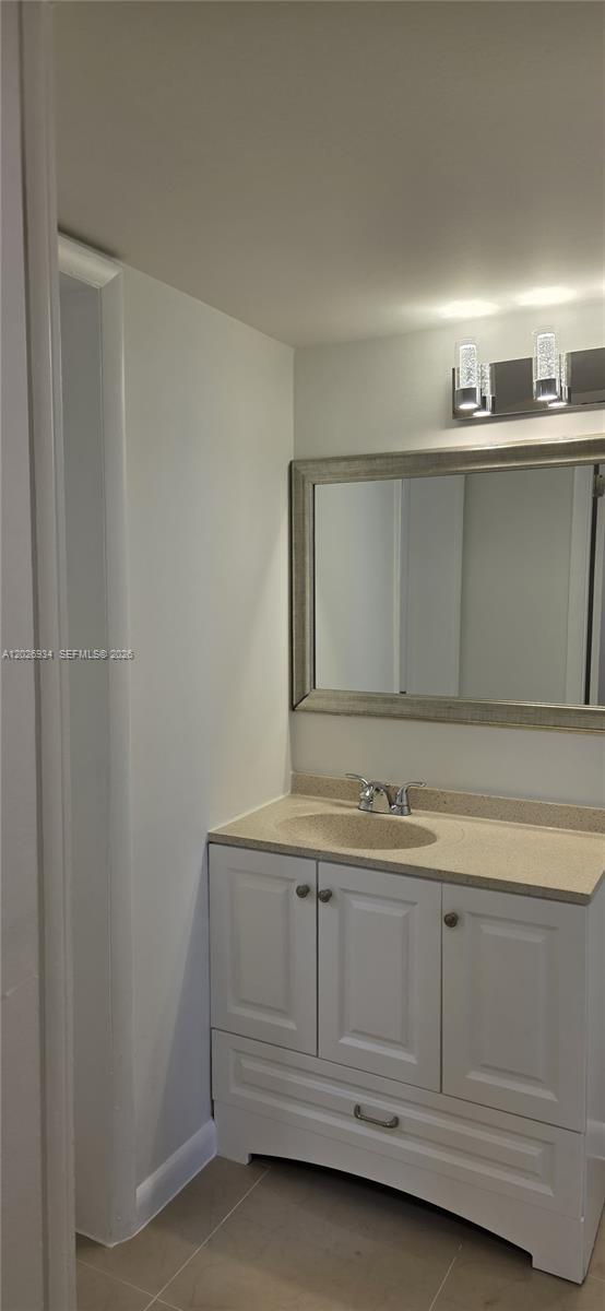 A bathroom features a white vanity with a beige countertop and a framed wall mirror — 492 NW 165th St Rd # 511, Miami FL 33169, MIAMI, FL
