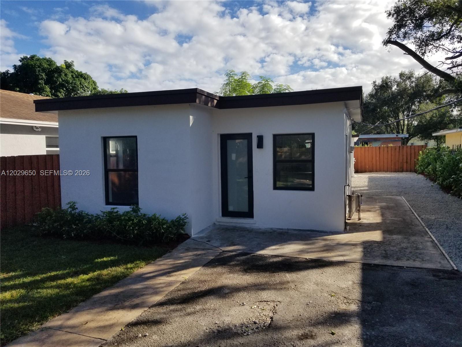 A small, white, flat-roofed detached structure features a glass door and two black-framed windows — 1756 NW 94th St, Miami FL 33147, MIAMI, FL