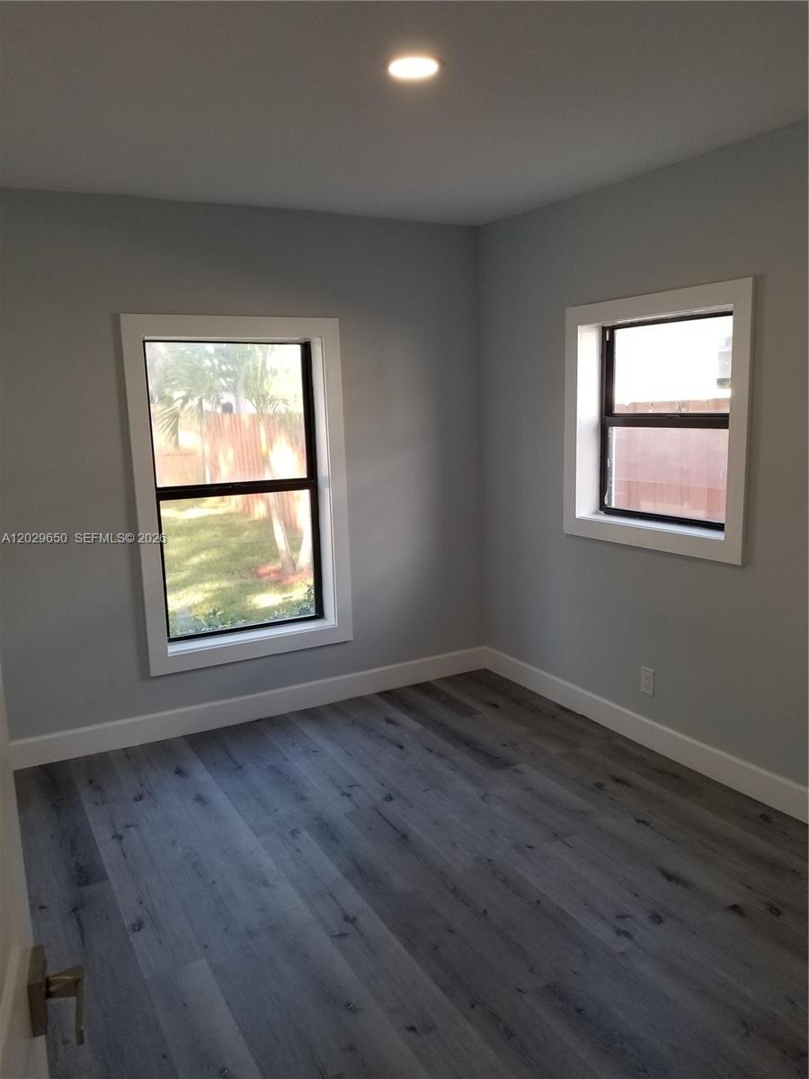 A bedroom features gray walls, wood-look flooring, white trim, and two windows — 1756 NW 94th St, Miami FL 33147, MIAMI, FL