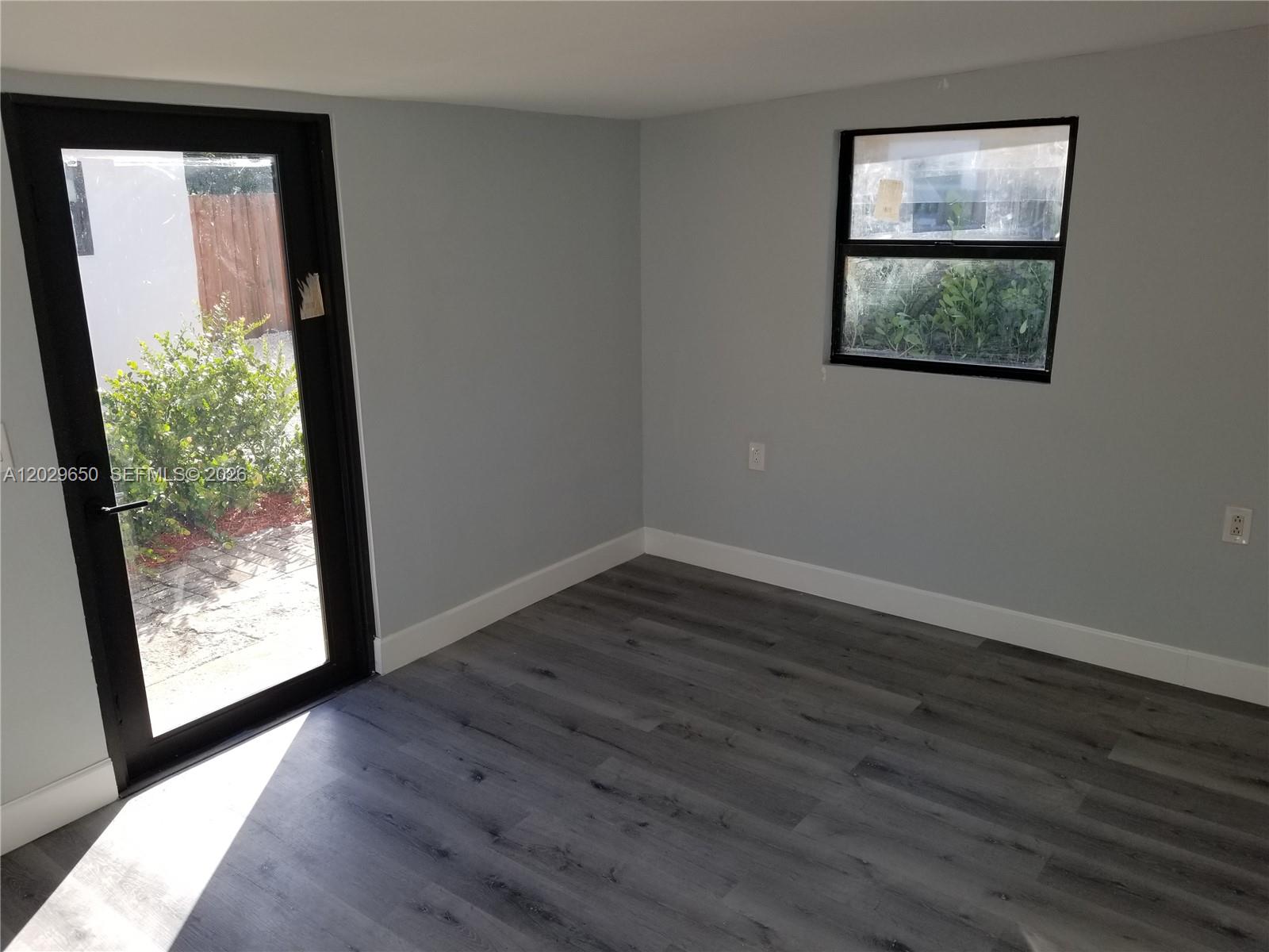 A room with gray walls, wood-look flooring, a glass door, and a single window — 1756 NW 94th St, Miami FL 33147, MIAMI, FL