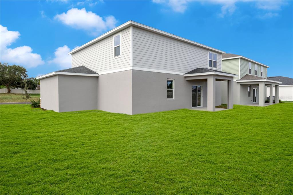 The exterior rear view of a two-story house with a covered patio and lawn — 995 CONNOLLY LANE, PALM BAY, FL