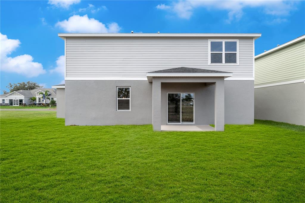 The rear exterior of a two-story house features gray siding, a covered patio, and lawn — 995 CONNOLLY LANE, PALM BAY, FL