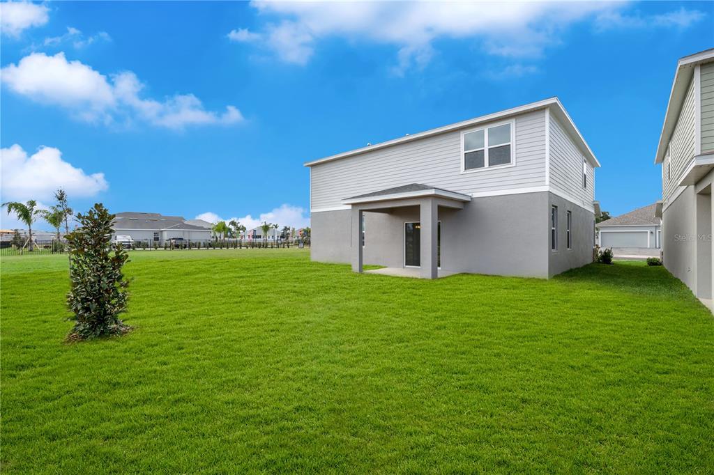 The exterior of a two-story house features gray siding and a covered back patio — 995 CONNOLLY LANE, PALM BAY, FL
