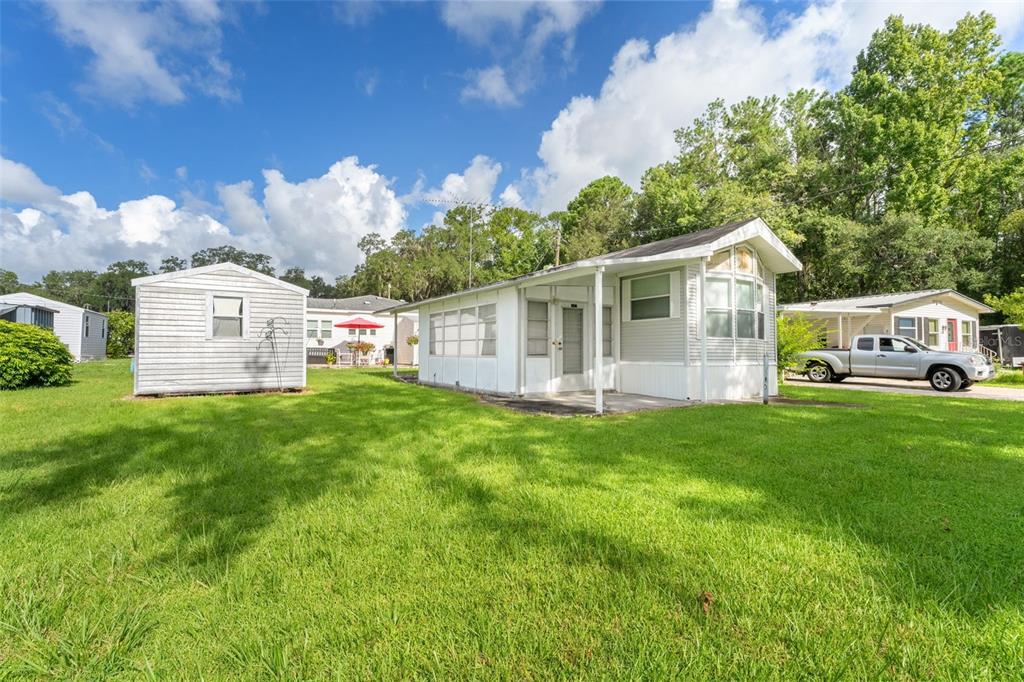 A white mobile home with an attached screened porch sits on a grassy lot — 2092 CULBREATH ROAD UNIT A27, BROOKSVILLE, FL