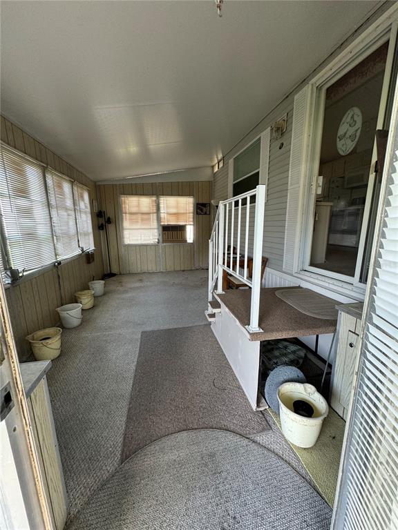 A covered porch features carpeted flooring, white railings, and several buckets placed along the wall — 2092 CULBREATH ROAD UNIT A27, BROOKSVILLE, FL