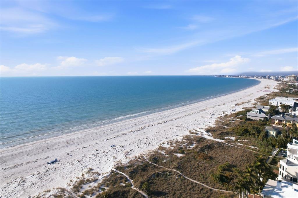 An aerial view shows a wide sandy beach meeting the ocean along a coastal town — 2906 PASS A GRILLE WAY, ST PETE BEACH, FL