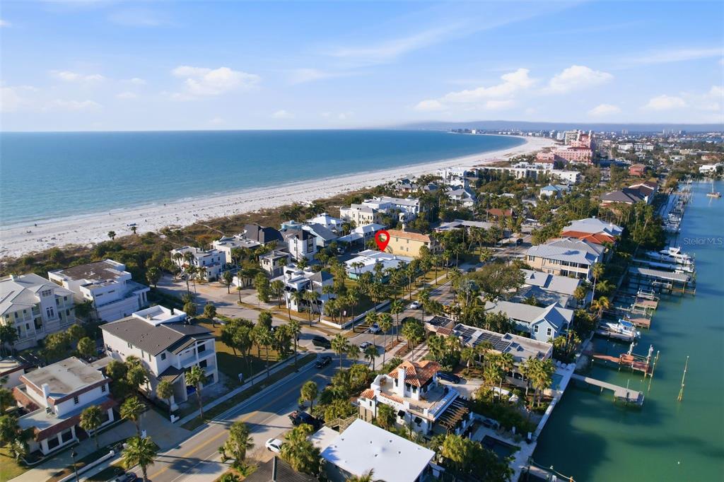 An aerial view shows a coastal neighborhood with houses situated between a beach and a bay — 2906 PASS A GRILLE WAY, ST PETE BEACH, FL