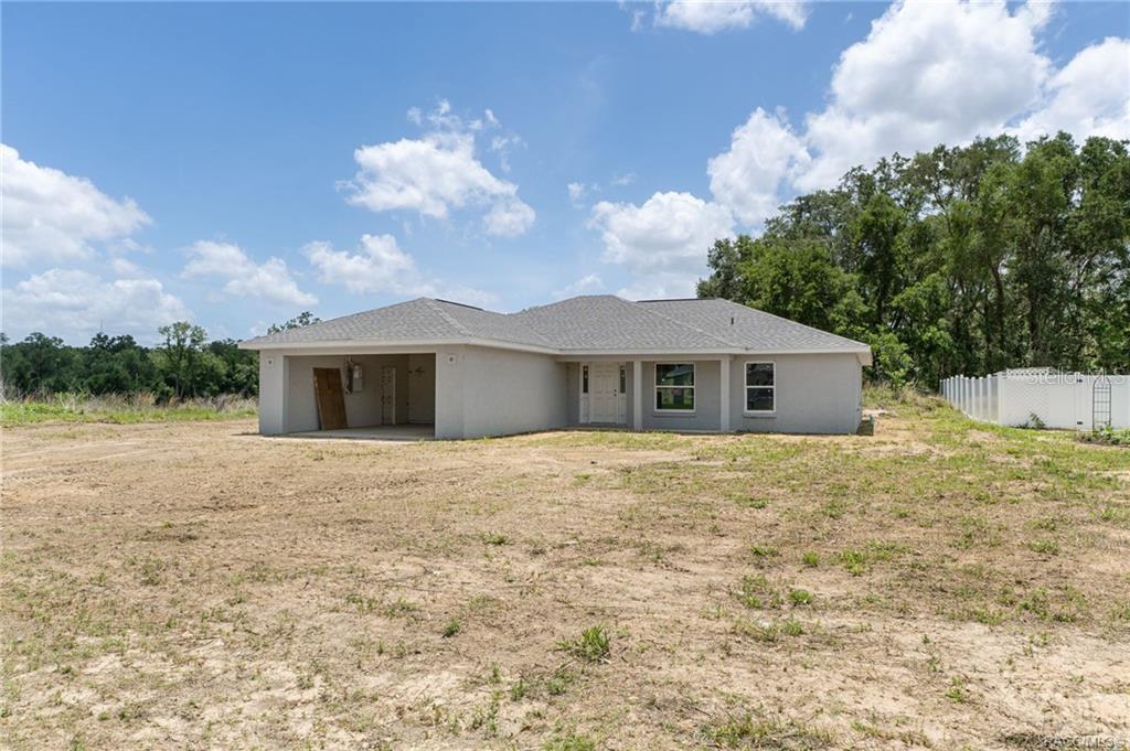 A single-story house with a gray exterior and attached garage sits on a dirt lot — 4452 E REJOICE STREET, INVERNESS, FL