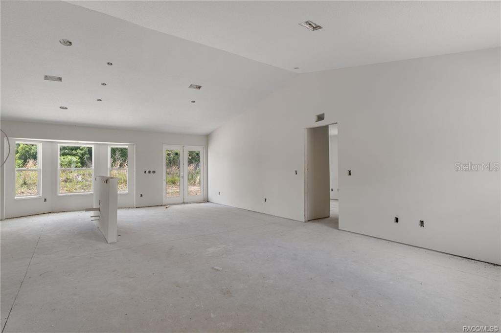 An unfinished room with a vaulted ceiling, concrete floors, and a kitchen island stub-out — 4452 E REJOICE STREET, INVERNESS, FL