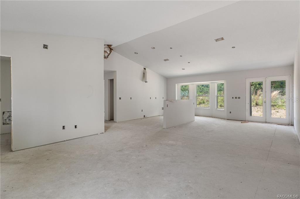 An unfinished interior room features white drywall, a partial wall, and glass patio doors — 4452 E REJOICE STREET, INVERNESS, FL