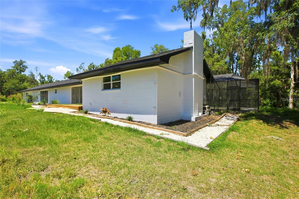 A white, single-story house with a chimney and a screened-in porch in a grassy yard — 8315 REVELS ROAD, RIVERVIEW, FL