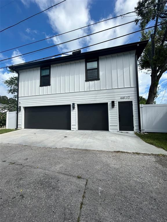 A two-story white building features a double garage, a single entry door, and dark trim — 468 44TH AVENUE N UNIT 1/2, ST PETERSBURG, FL