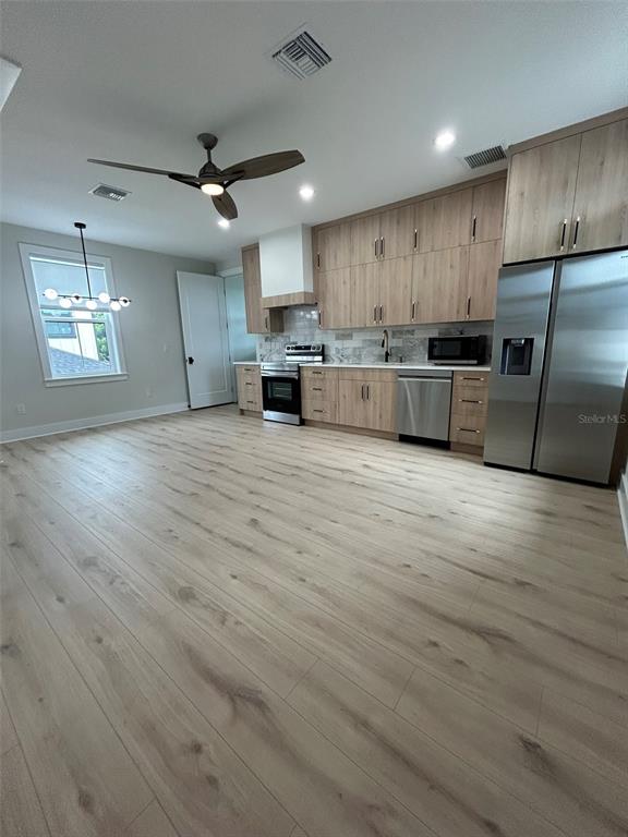 A modern kitchen features light wood cabinetry, stainless steel appliances, and wood-look flooring — 468 44TH AVENUE N UNIT 1/2, ST PETERSBURG, FL