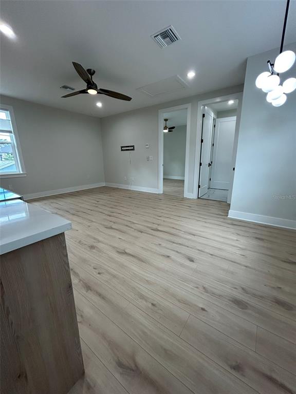 A bright, open-concept living area features light wood-look flooring, a ceiling fan, and modern lighting — 468 44TH AVENUE N UNIT 1/2, ST PETERSBURG, FL